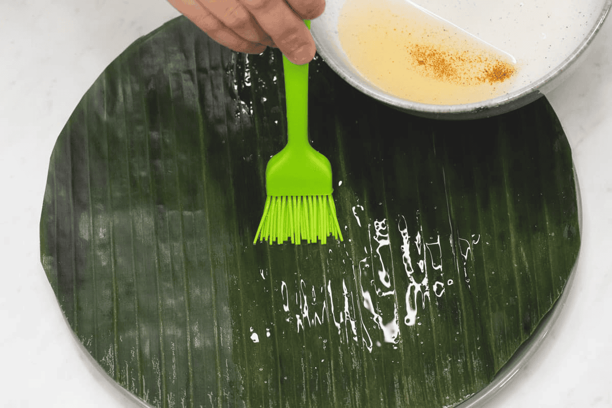 Brushing the banana leaves with coconut oil.