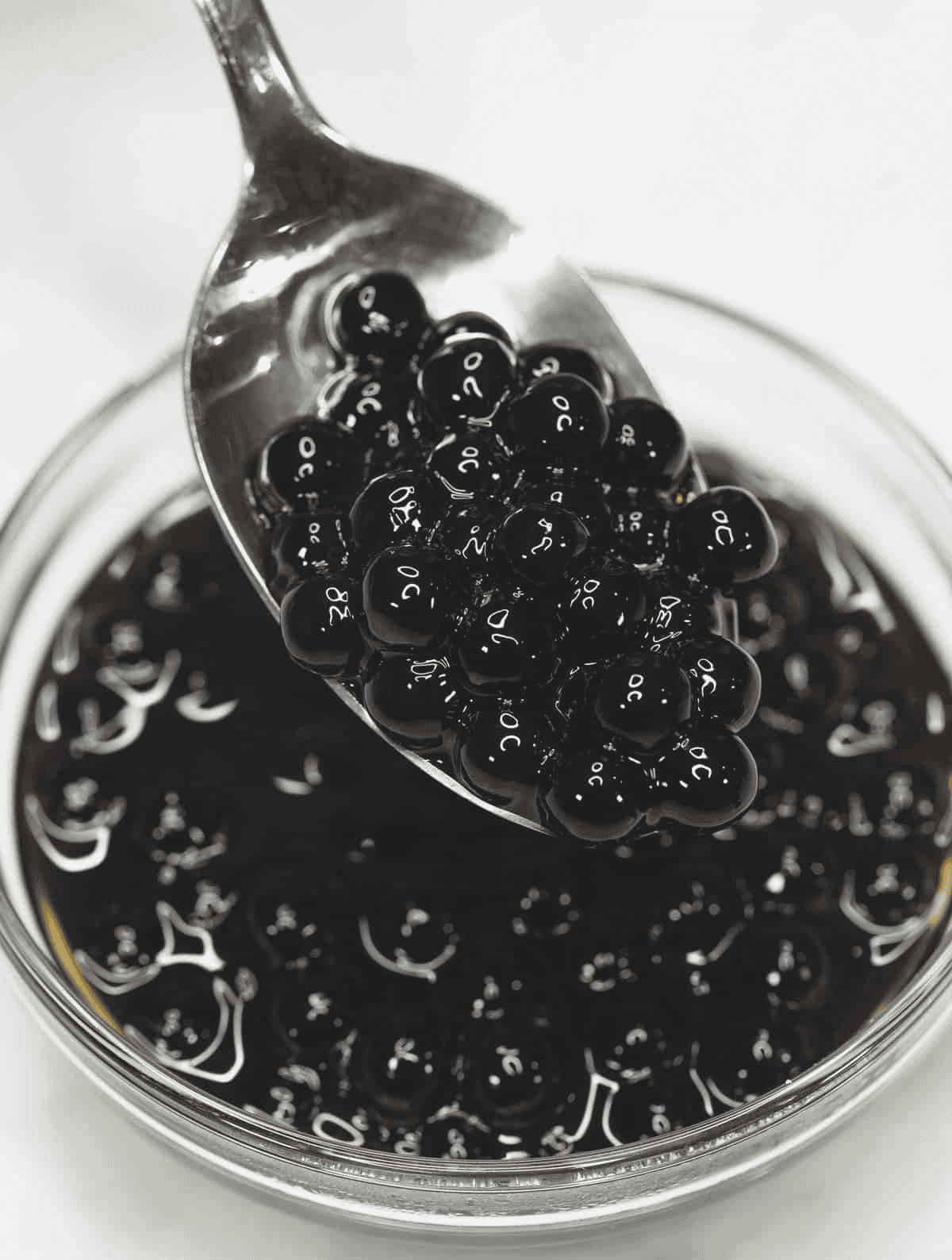Tapioca pearls in brown sugar syrup on a spoon and in a bowl.
