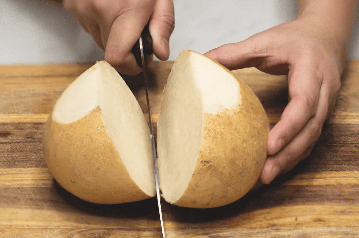 cutting jicama in half on a cutting board.