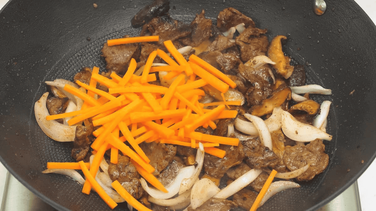 Added carrots to the beef and onions in the wok.