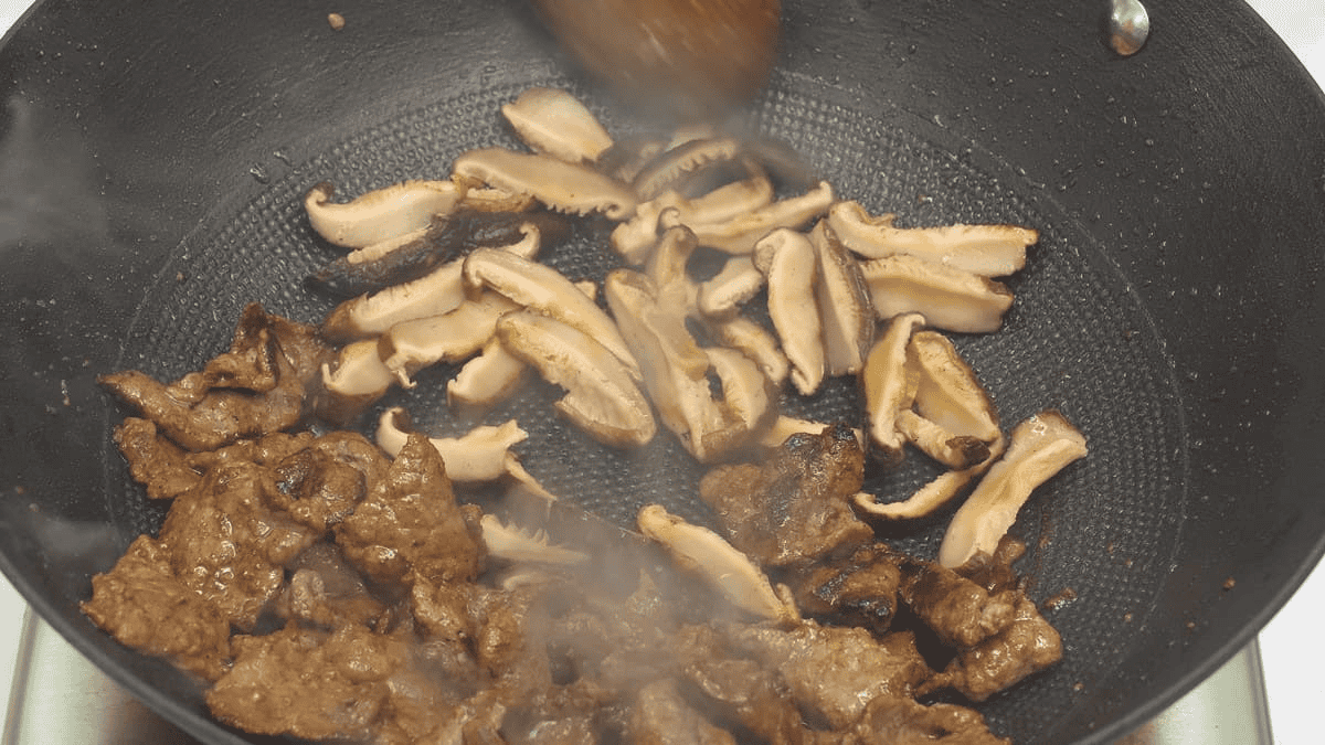 Searing the mushrooms with the beef in the wok.