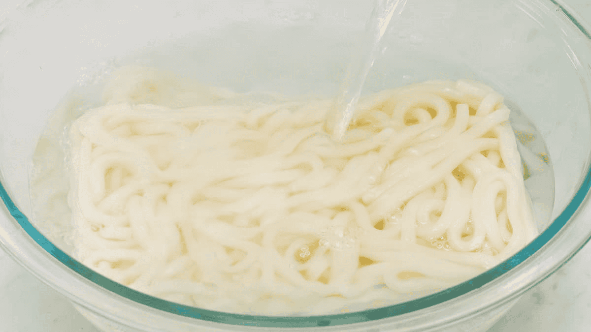 Pouring hot water to the frozen udon noodles in a bowl.