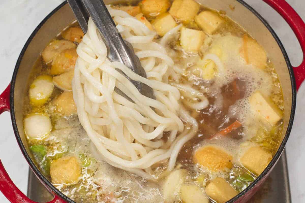 Adding the udon noodles to the soup.