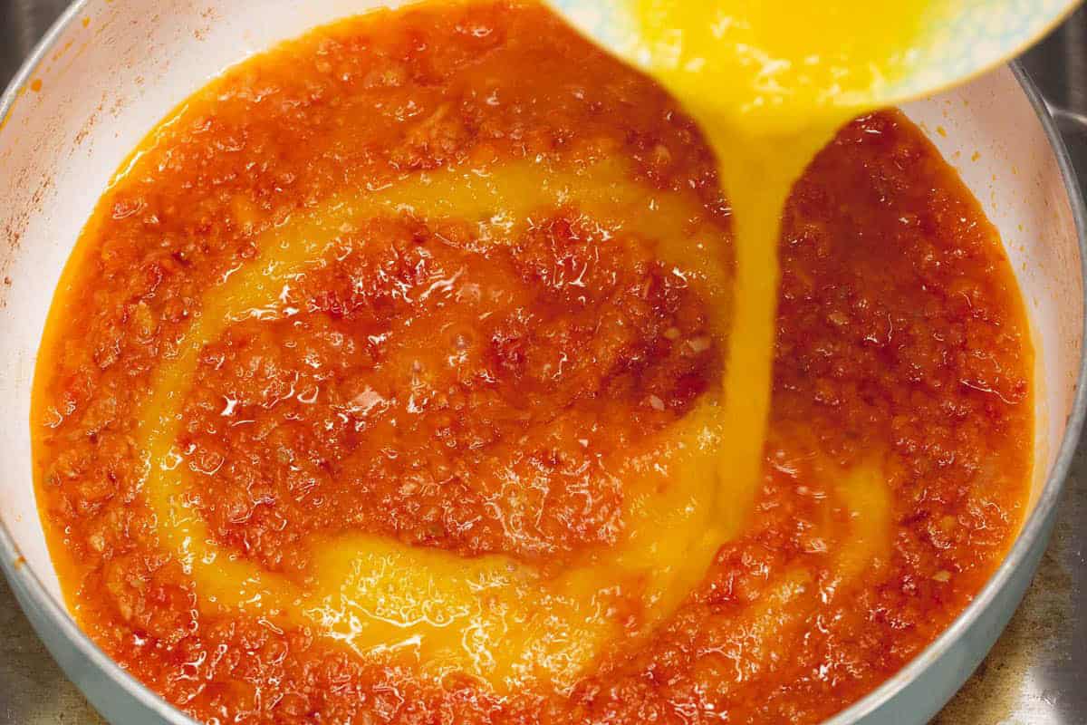 Adding the scrambled eggs in a circular motion into the mixture.