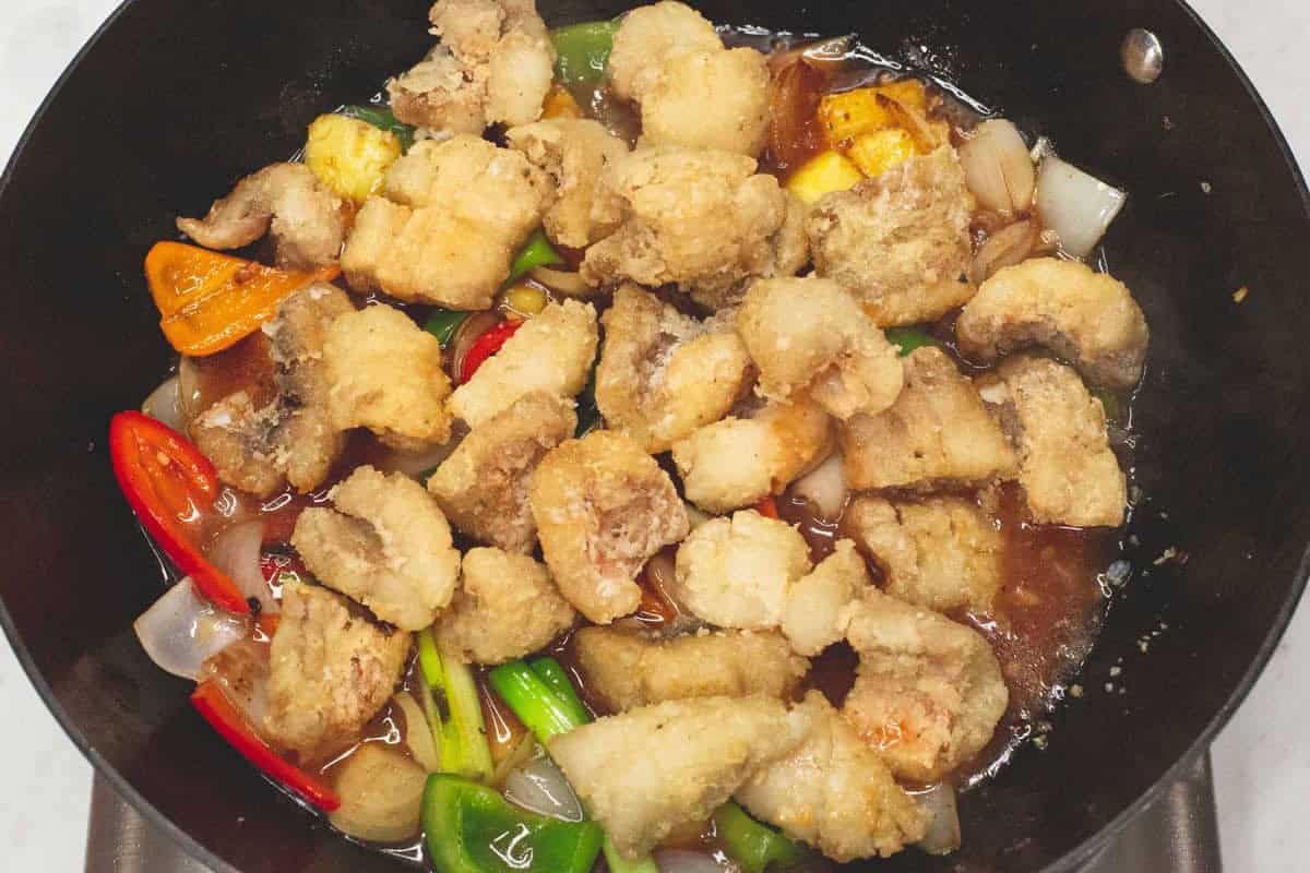 Added the fried fish to the mixture in the wok.