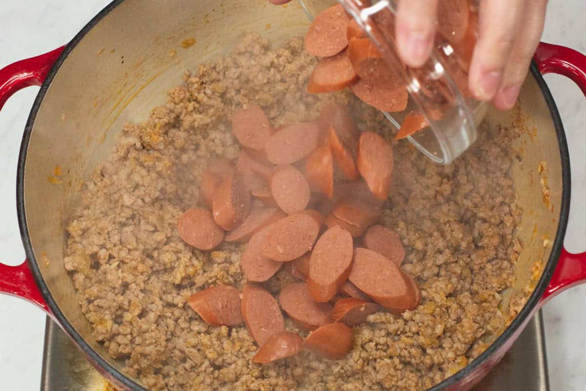 Adding the hotdogs to the pot.