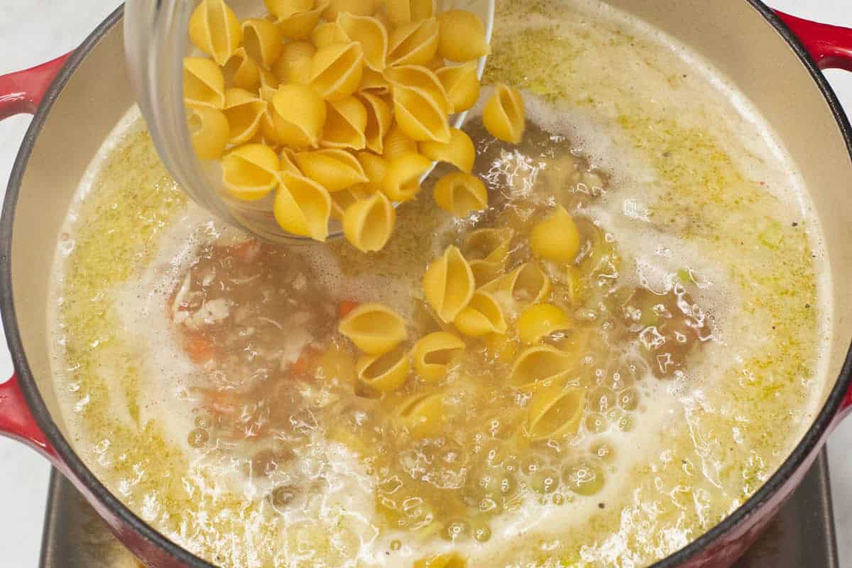 Adding the pasta to the boiling mixture in the pot.