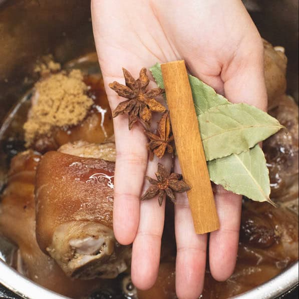 Adding the spices in a mesh bag to the mixture in the pot.
