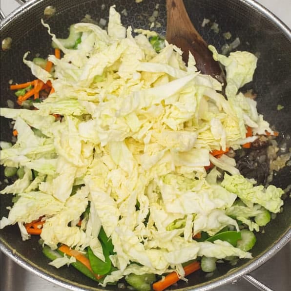 Stir frying the vegetables in a wok, then added the cabbage to the mix. 