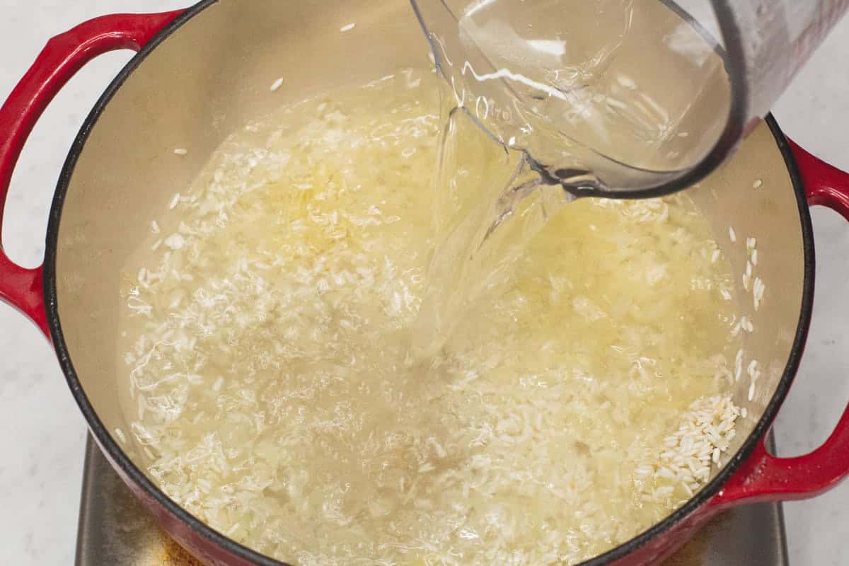 Adding water to the mixture in the pot.