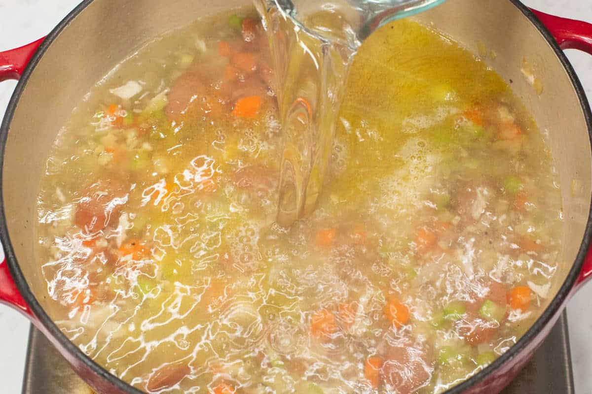 Adding water to the mixture in the pot.