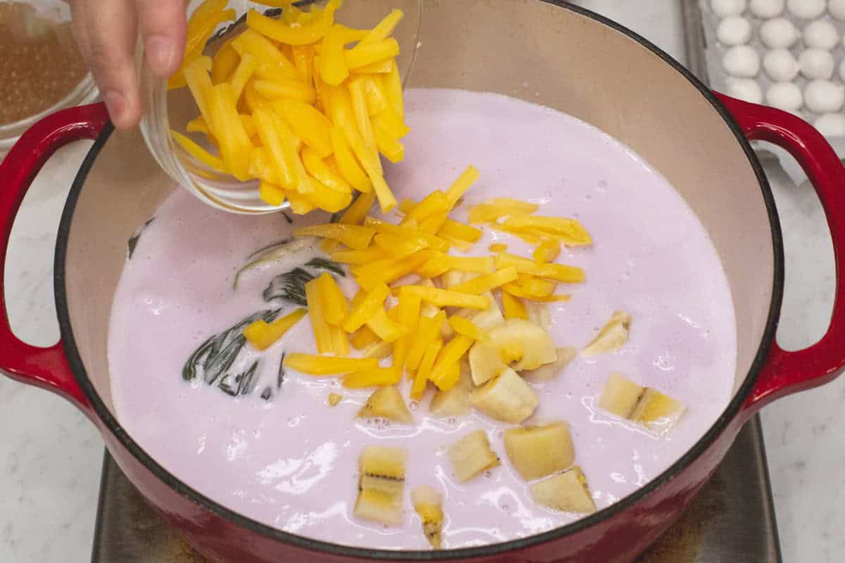 Adding the saba bananas and jackfruit to the mixture.