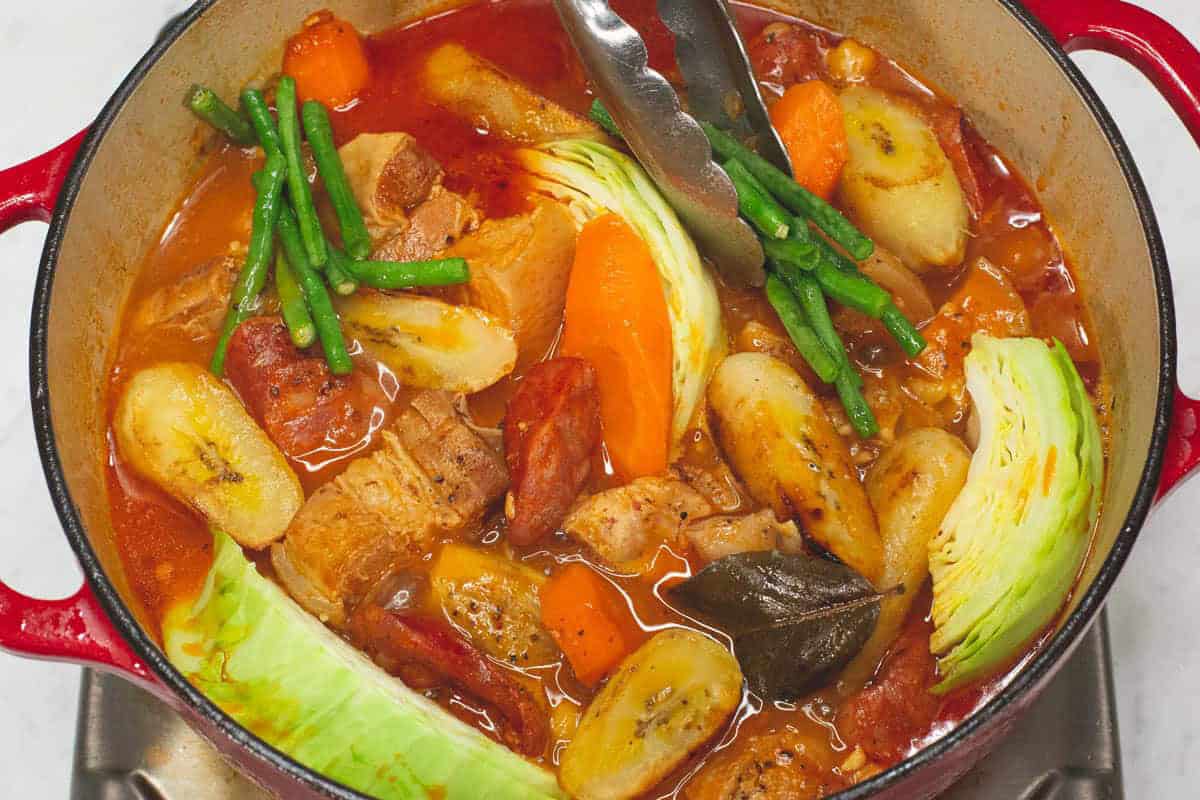 Adding yardlong beans to the meat and other ingredients in the pot.