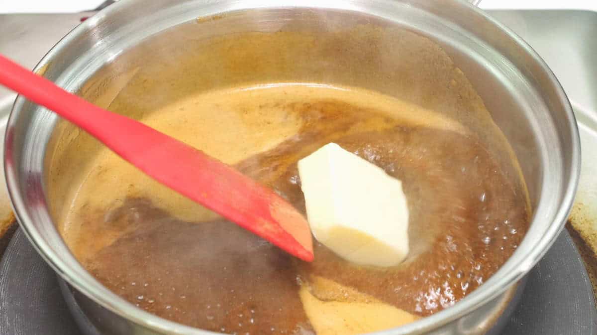 Adding butter to the boiling marinade in the saucepan.