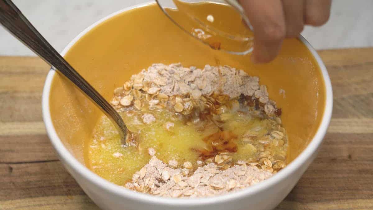 Adding vanilla to the oat streusel topping in the bowl.