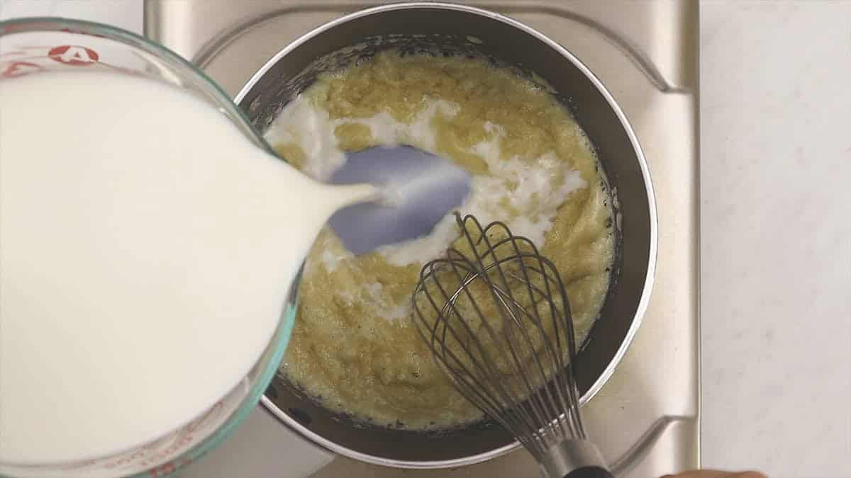 Adding the milk to the roux in the saucepan.