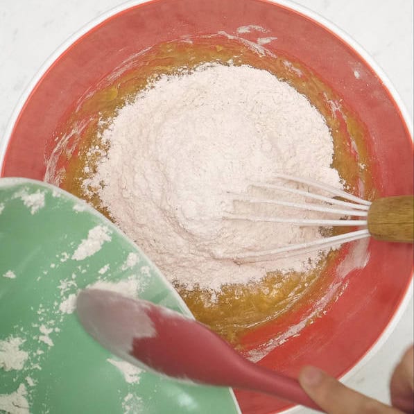 Combining the dry and wet ingredients in a bowl. Mixing the dry and wet ingredients using a whisk.