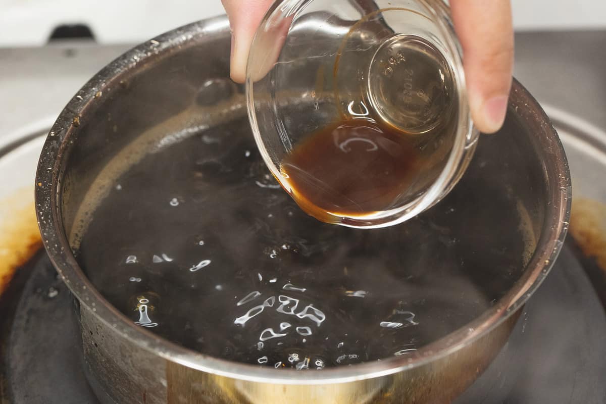 Adding vanilla extract to the brown sugar mixture in the saucepan.