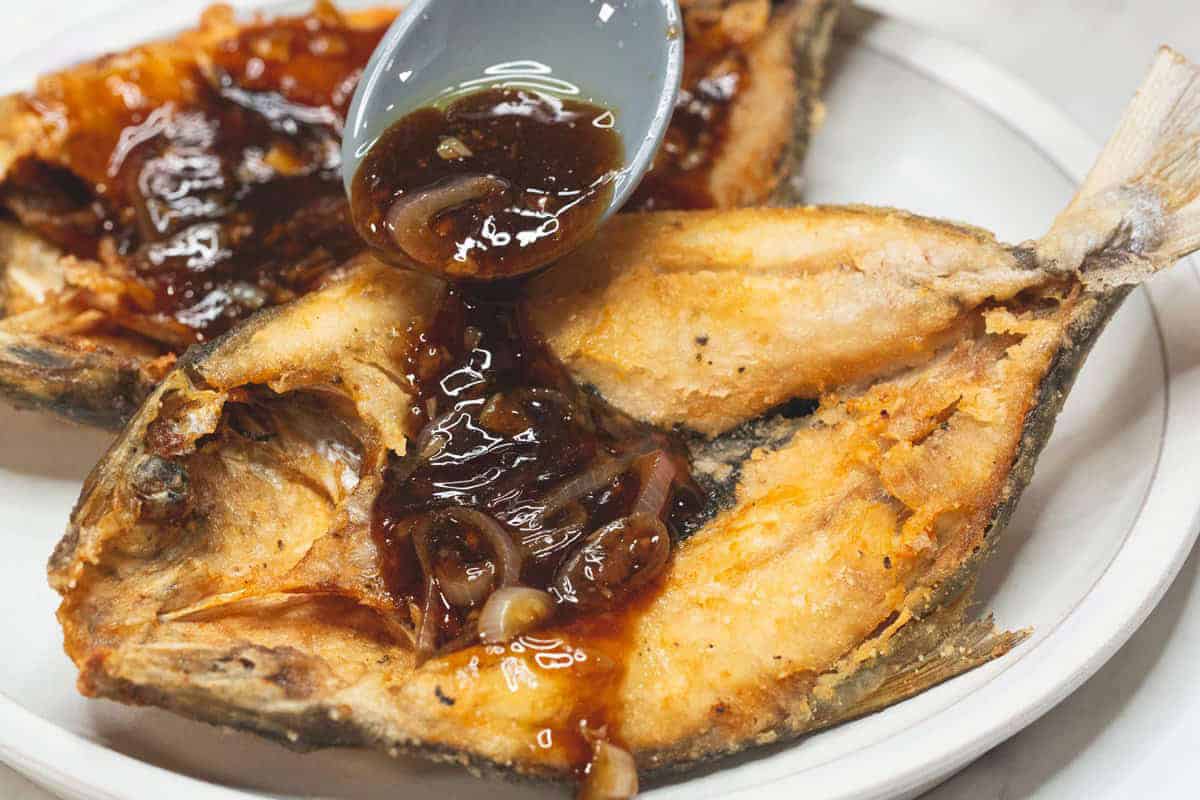 Pouring the sauce over the fried bangus.