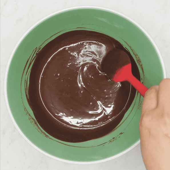 Stirring smooth chocolate ganache with a spatula.