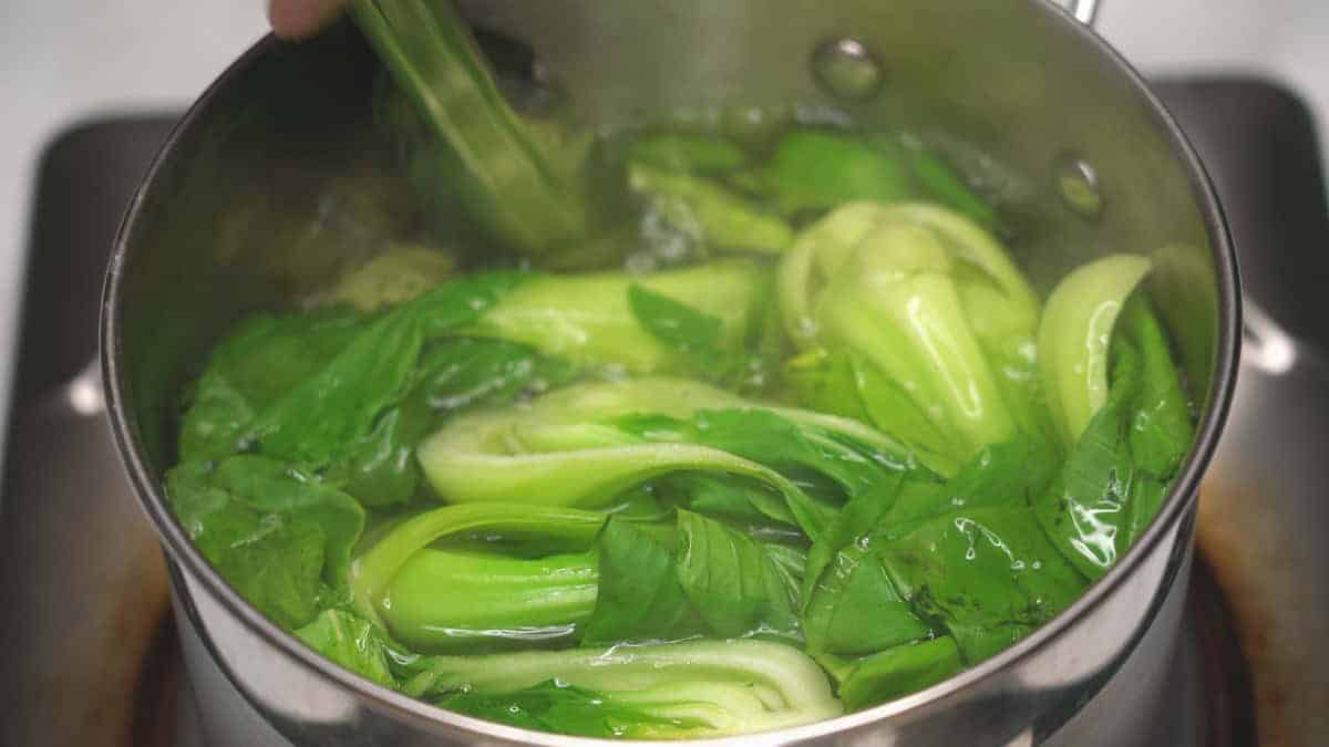 Blanching bok choy in boiling water.