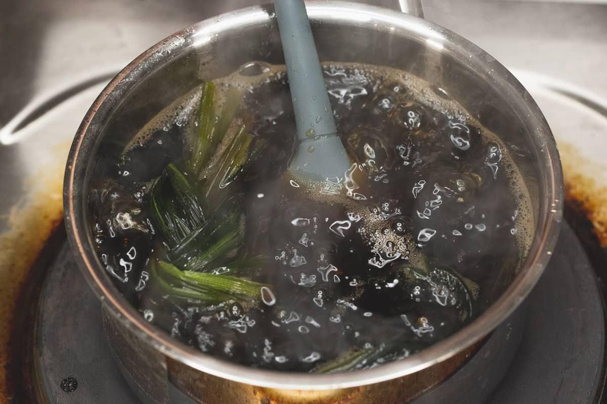 Boiling the ingredients for brown sugar syrup (arnibal) in a saucepan.