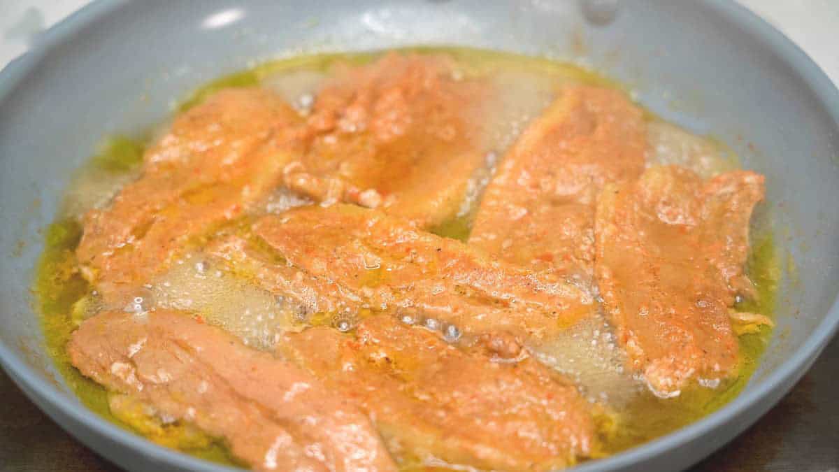 Cooking the tocino in water in the skillet.