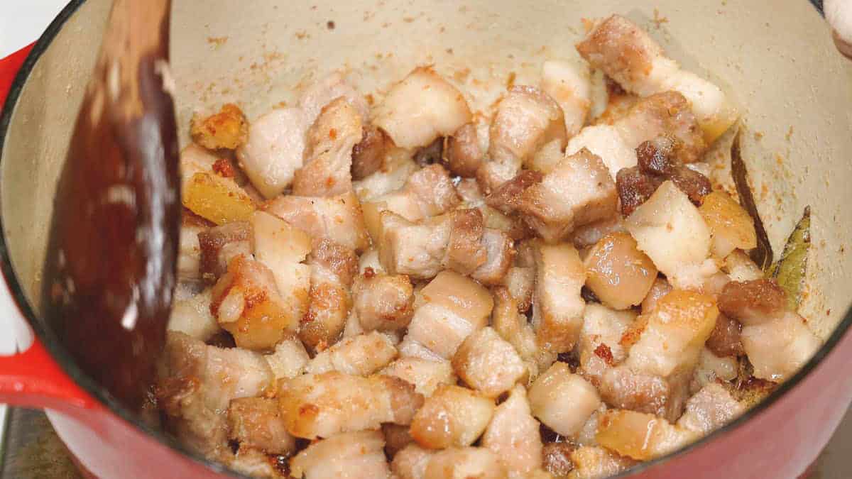 Rendering the fat and browning the meat in the pot.