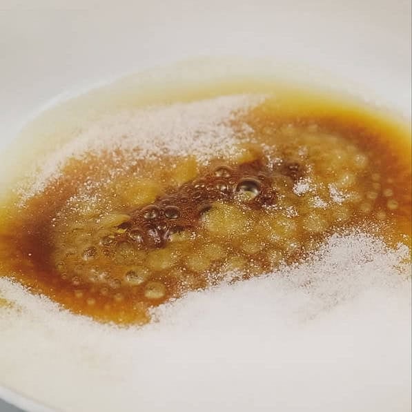 Caramelizing sugar on the pan. Coating the turon in caramel.