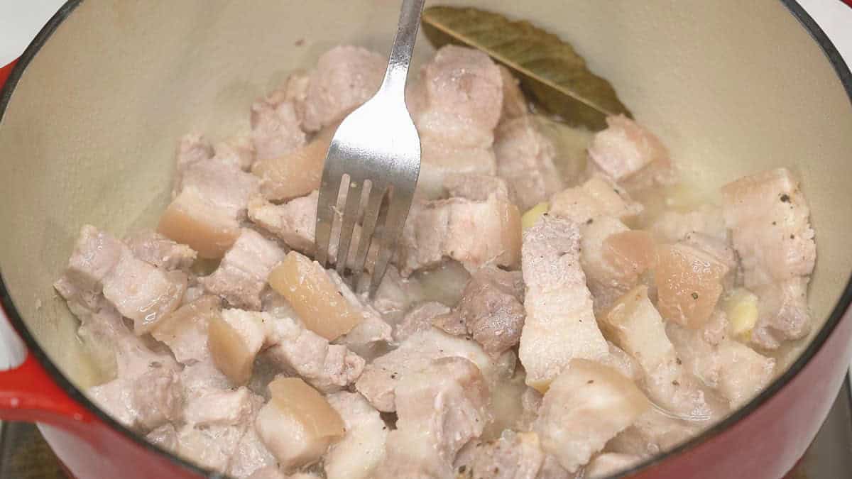Checking if the meat is tender using a fork.