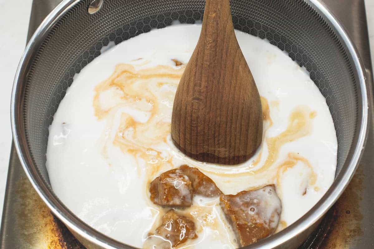 Mixing panutsa with the coconut milk in the saucepan.