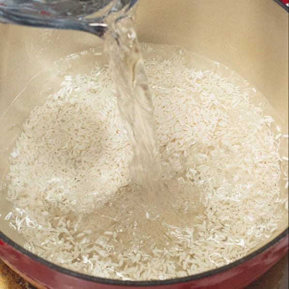 Adding water to the glutinous rice in the pot. Mixing the simmered glutinous rice in the pot.