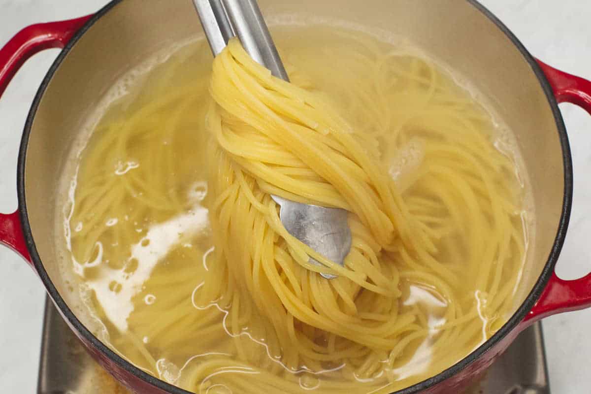 Lifting the pasta fom the water in the pot.