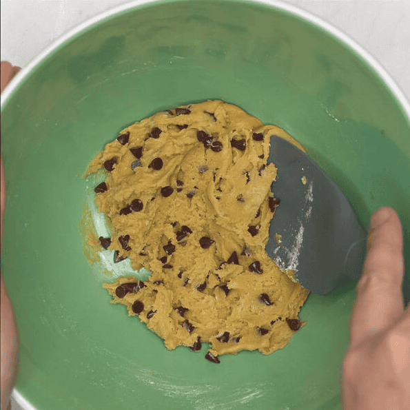 Mixing chocolate chips into cookie dough.