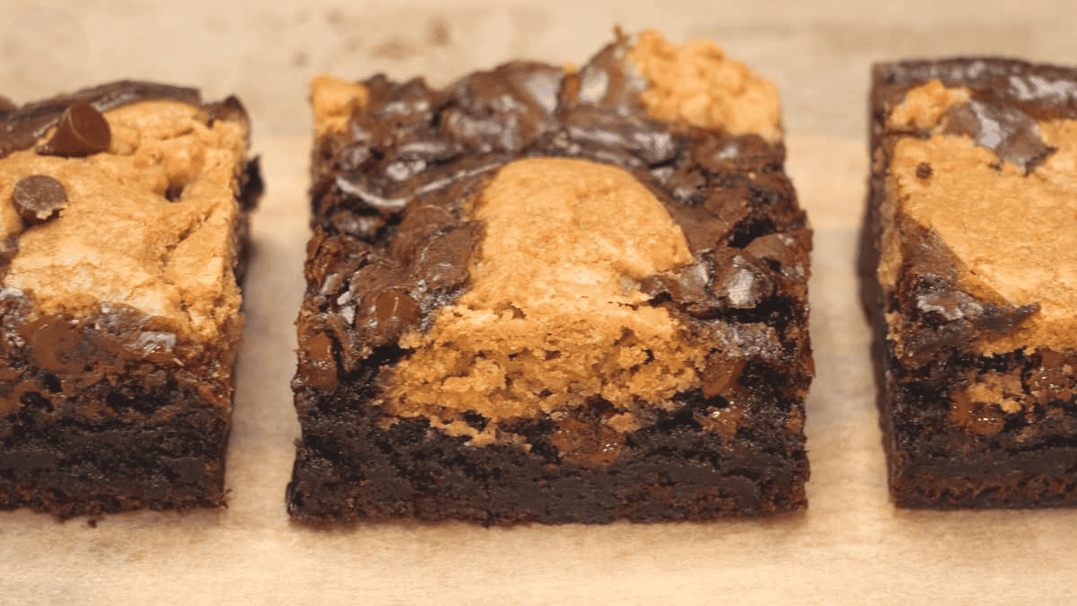 Slices of cookie brownie bars on parchment paper.