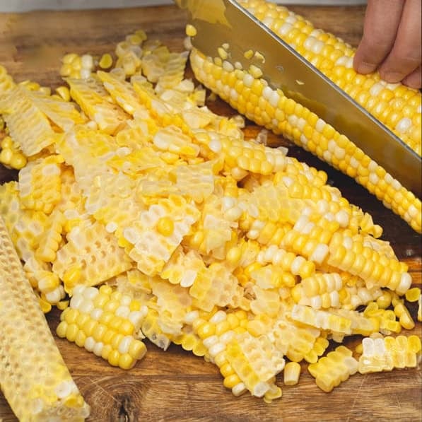Slicing corn kernels off the cob and coarsely grinding them using an immersion blender.