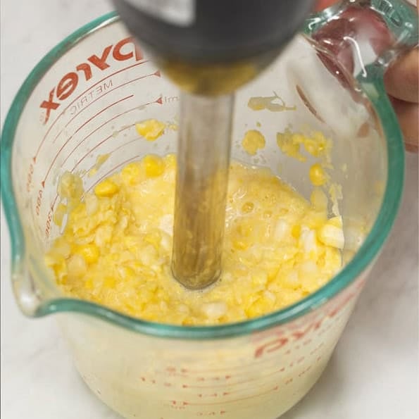 Slicing corn kernels off the cob and coarsely grinding them using an immersion blender.