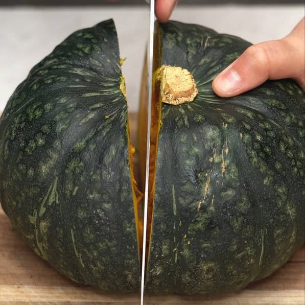 Cutting kabocha squash in half, then scooping the seeds with a spoon.