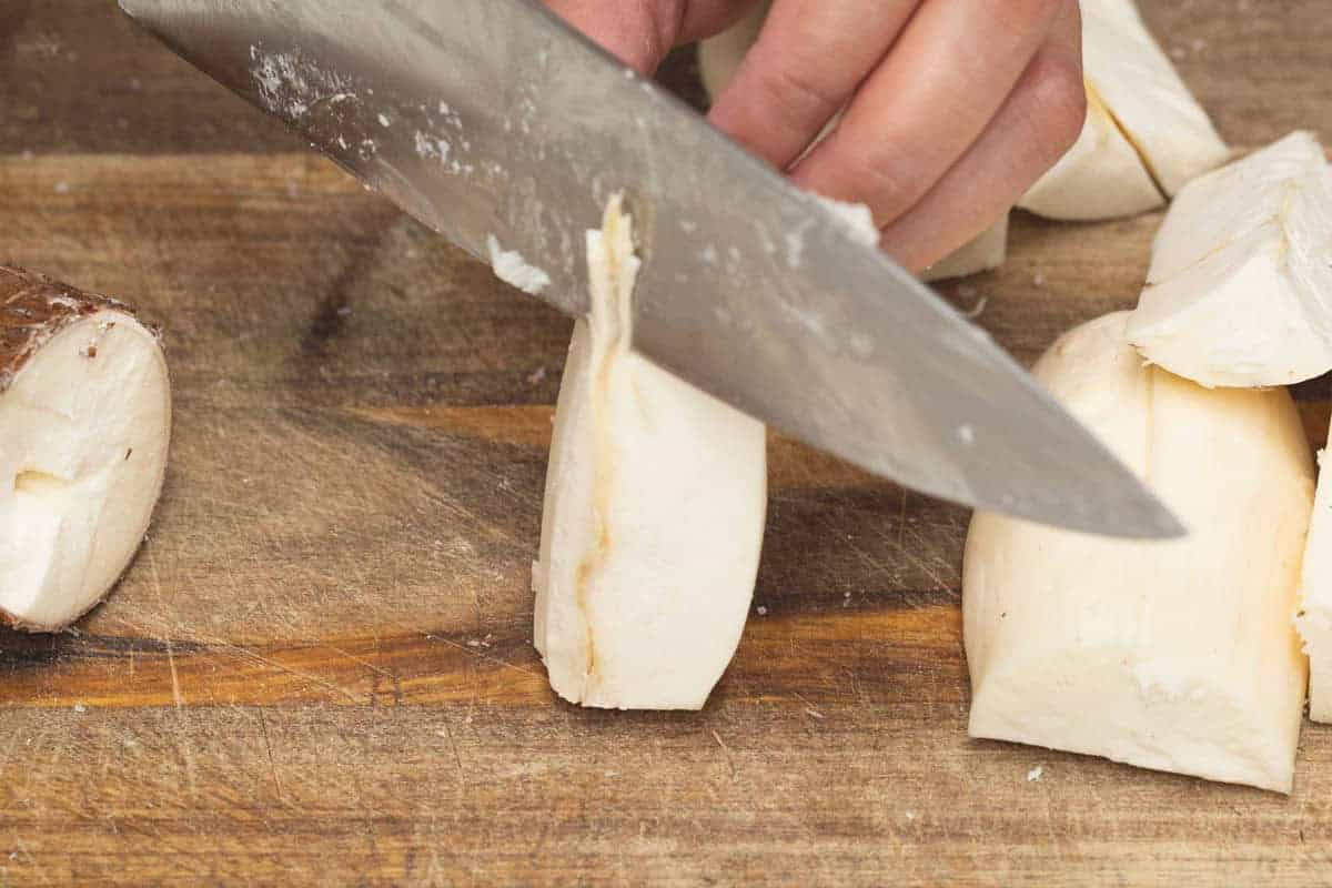 Removing the cassava core using a knife on a cutting board.