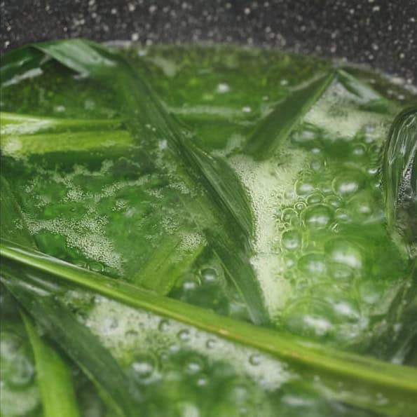 Adding agar-agar powder to the water in a saucepan. Boiling agar-agar and pandan leaves in a saucepan.
