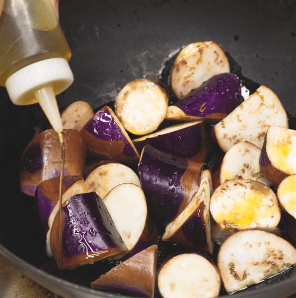 Adding oil to the steamed eggplant.