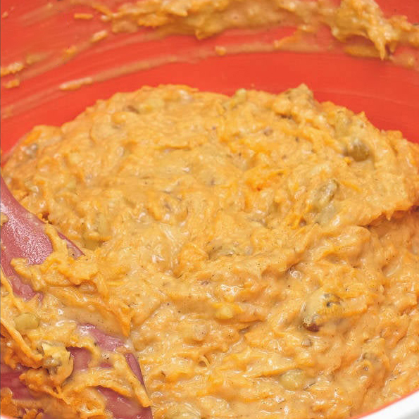Added nuts, pineapple, and carrots to the mixture in the bowl. Mixing the cake batter using a spatula.