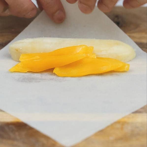 Banana slice and jackfruit strips on a spring roll wrapper. Folding the sides of a spring roll wrapper.