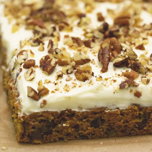 Spreading the cream cheese frosting onto the cake. Carrot sheet cake with cream cheese frosting topped with nuts.