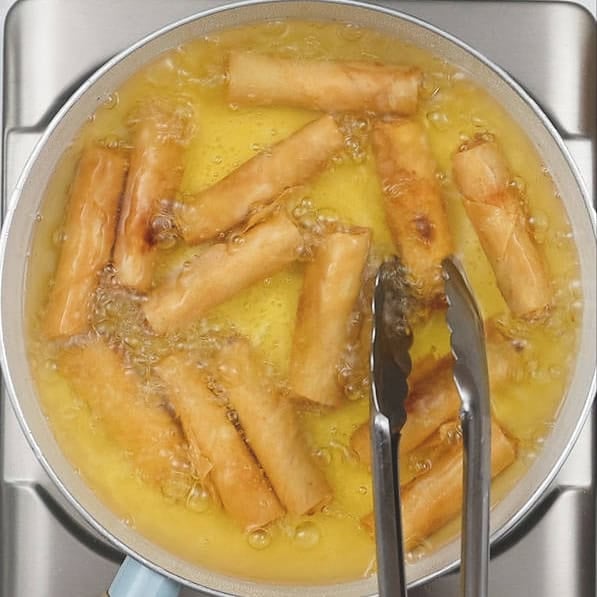 Flipping the turon in oil. Draining the excess oil of the turon on paper towels.