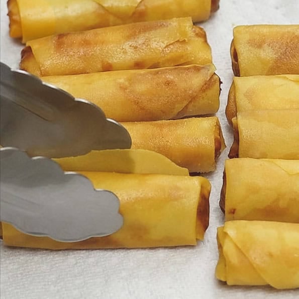 Flipping the turon in oil. Draining the excess oil of the turon on paper towels.