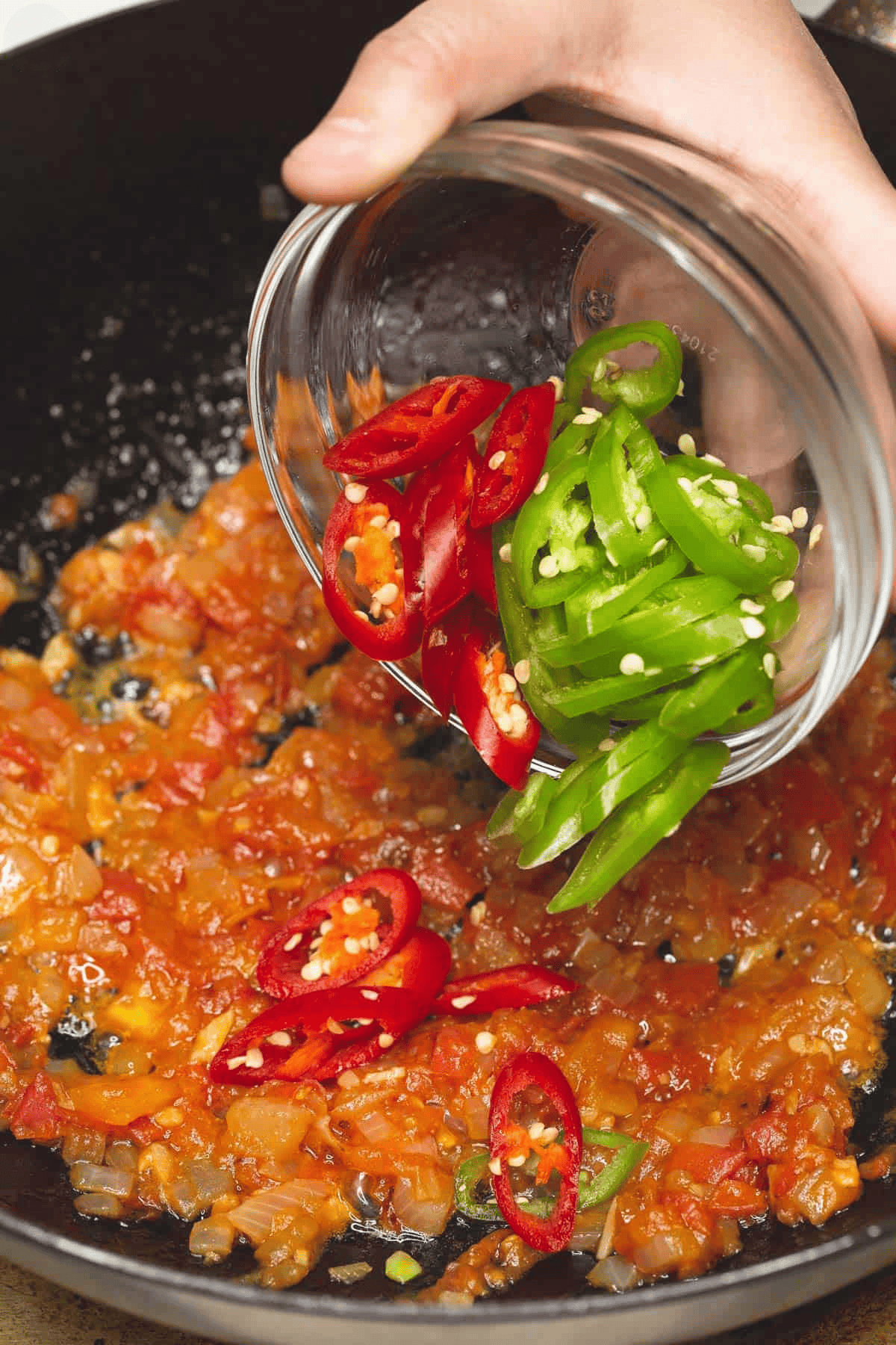 Adding chili peppers to the sauteed aromatics in the wok.