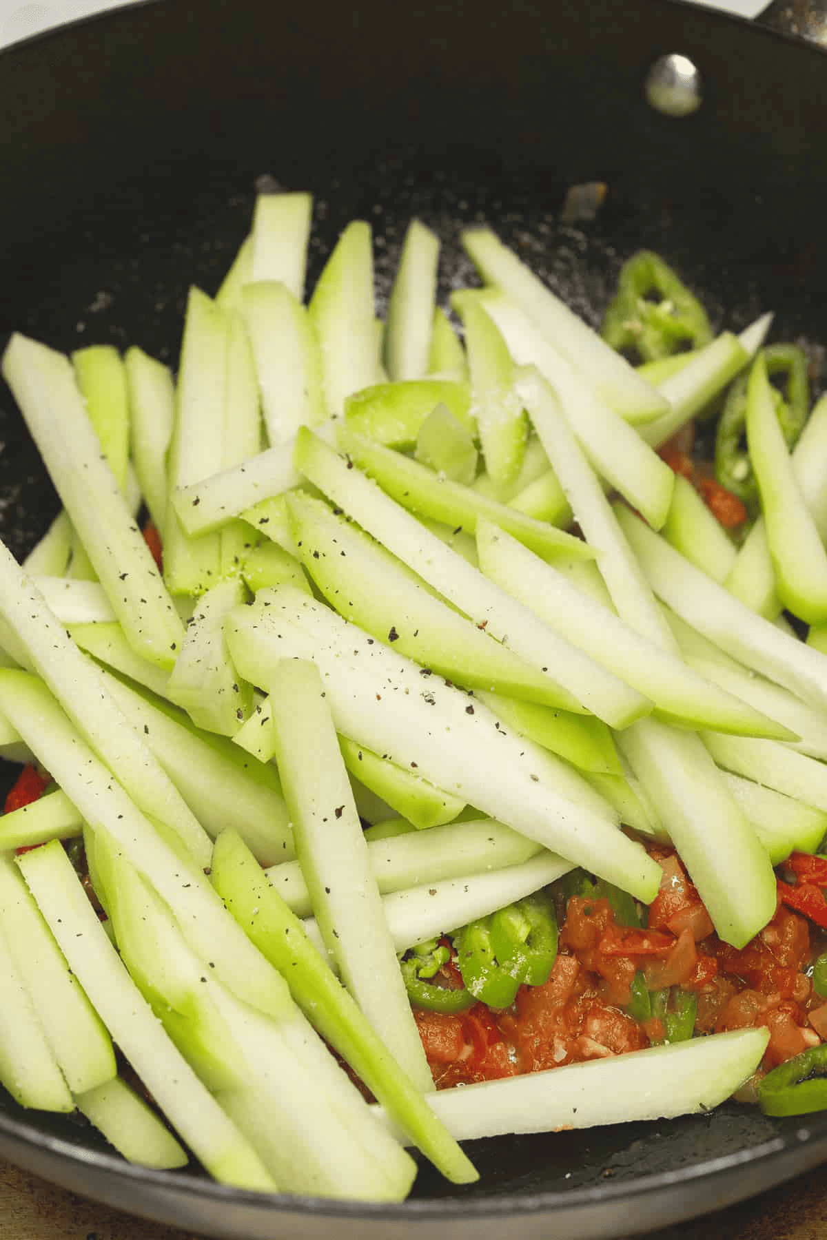 Chayote and other ingredients in the wok.