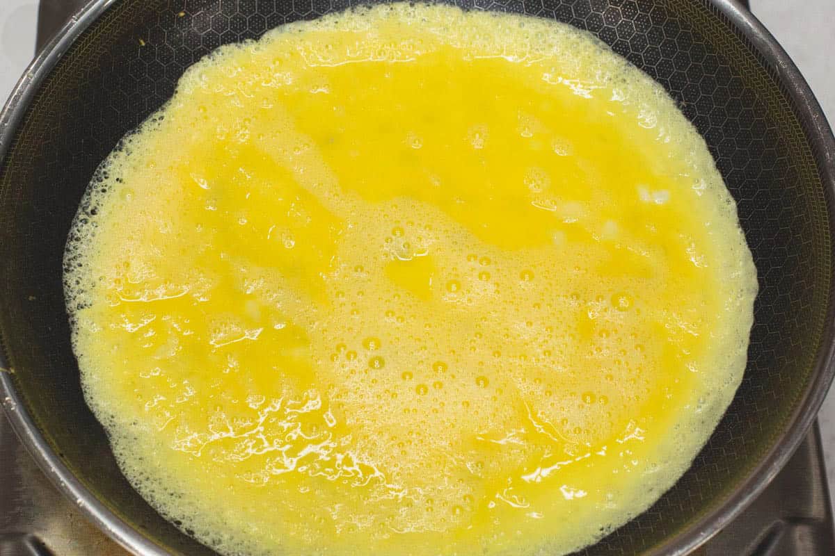 Frying the beaten eggs in a skillet.