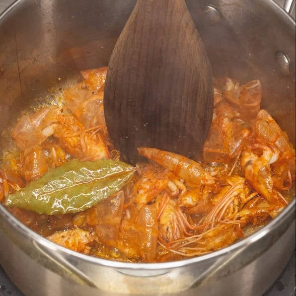 Sauteing the shrimp heads and shells. Boiling the stock in the saucepan.